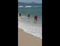 Woman photographs two men at beach 