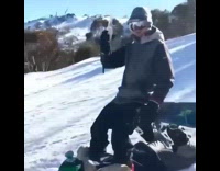 Guy sits on friend snowboard like chair 