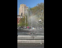 Guy lays in the middle of water fountain