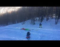 Skier red jacket green pants backflips off ramp and faceplants into the snow