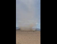 Guys film dust devil on open field