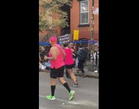 Guy holding a fake trump doll and sign telling runners to punch