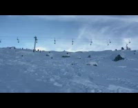 Guy rides skis over rock land on butt 