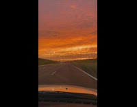 Guy drives car down street towards sunset