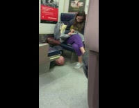 Crazy guy slides under train chairs and causes woman to move seats