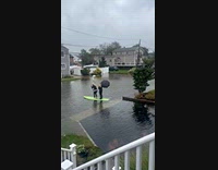 Two women uses paddleboard on flooded street