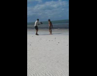 Man shirtless backflips at the beach shore