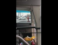 Man red poncho plays guitar and sings in the middle of street