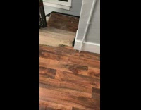 Woman sweeps rain water leaks in apartment