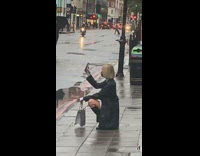 Woman black coat selfie squat sidewalk rain