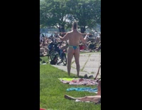 Guy in blue and green speedo meditates with stick