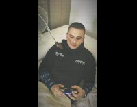 Guy plays games on the couch and has oscillating fan feed him Nutella