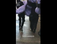 Three guys carry giant purple statue figure down New York sidewalk