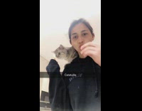 Girl gives grey cat on shoulders carrot 