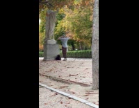 Man with beanie dances near park statue