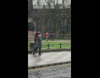 Man in red jacket raps in front of war memorial