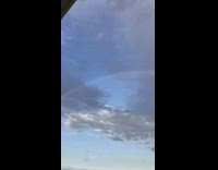 Full rainbow arch over farm fields overcast