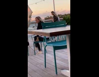 Girl dances on restaurant patio by ocean 