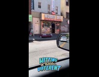 Guy lays on small mattress on sidewalk 