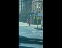 Guy in red fur coat dances to maniac on sidewalk corner