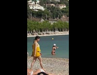 Woman in black bikini splashes water at the beach