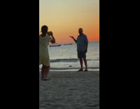 Woman takes picture of husband holding sun sunset