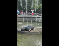 Guy lays on fountain with wetsuit