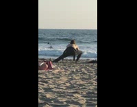 Collab Kook Of The Day - Black wetsuit guy stretches lunges beach sand 