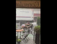 Lady sits restaurant patio table rain barefoot 