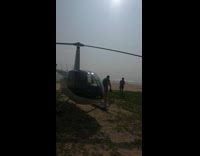 Parked helicopter on grass dirt windy 