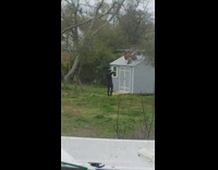 guy sits on shed with red guitar