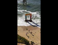 Girl runs onto arch in ocean and gets splashed by big wave