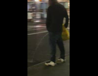 Guy standing on sidewalk pees on street 