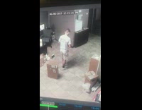 Security camera, guy steps on bottle and kicks bottle into the air, records with phone