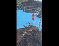 Woman red outfit dances near beach fence