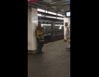 Collab Subway Creatures - Guy with long feather on head plays flute with clothing rack in subway station