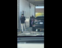 Woman poses beside car at car wash