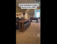 Two guys trying to keep balloon from touching floor 