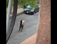 Shirtless man direct car traffic on street