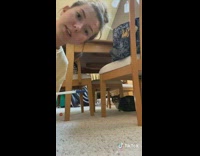 Black cat under table doesnt want to take medicine