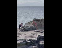 Man in red briefs jumps on the rock at the beach