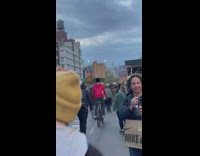 Guy rides bike and balances box in middle of march