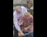 Older couple playing with water hose backyard 