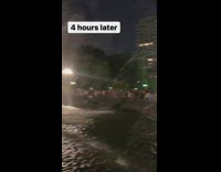 Guy standing in water fountain spins stick 