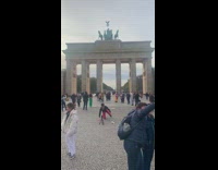 Man in black leather jacket crouches to the camera at the park