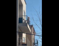 Man shaves beard using razor at balcony