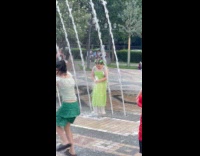 Kid playing on fountain gets dress lifted by water