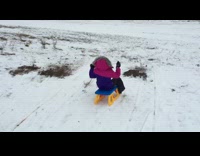Kid sleds down slope and falls
