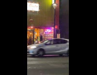 Man reads neon sign open while stuck on traffic