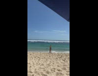 Man in speedos film woman running on beach